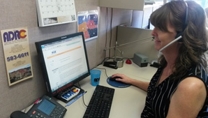 Woman at Desk on Computer with Headset on 